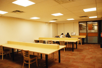 Newly-painted space with new carpets, long table, and wood chairs.