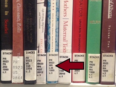 Spines of library books on a shelf, with an arrow pointing to the call number section of one.