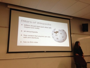 A powerpoint slide projected on a screen, "Pillars of Wikipedia"