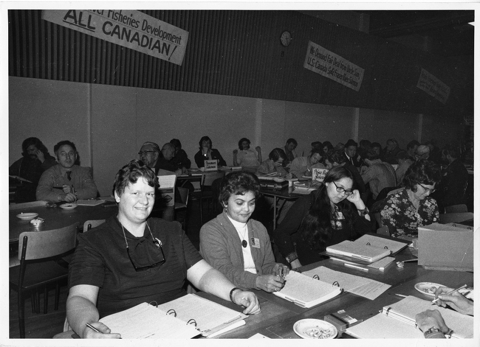 UFAWU members sitting at tables in a hall attending an annual convention. The tables are covered in notebooks and binders