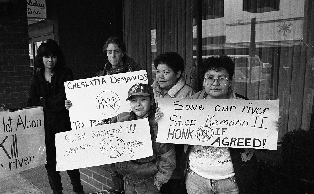 Five protestors from Cheslatta Carrier Nation emonstrate outside Utilities Commission hearing holding four protest signs