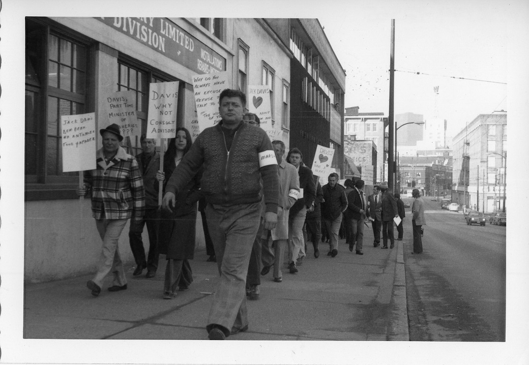 Group of protestors walking down a street in demonstration holding many signs