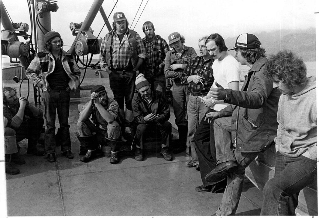 Group of fishers standing and sitting on the deck of a fishing boat 