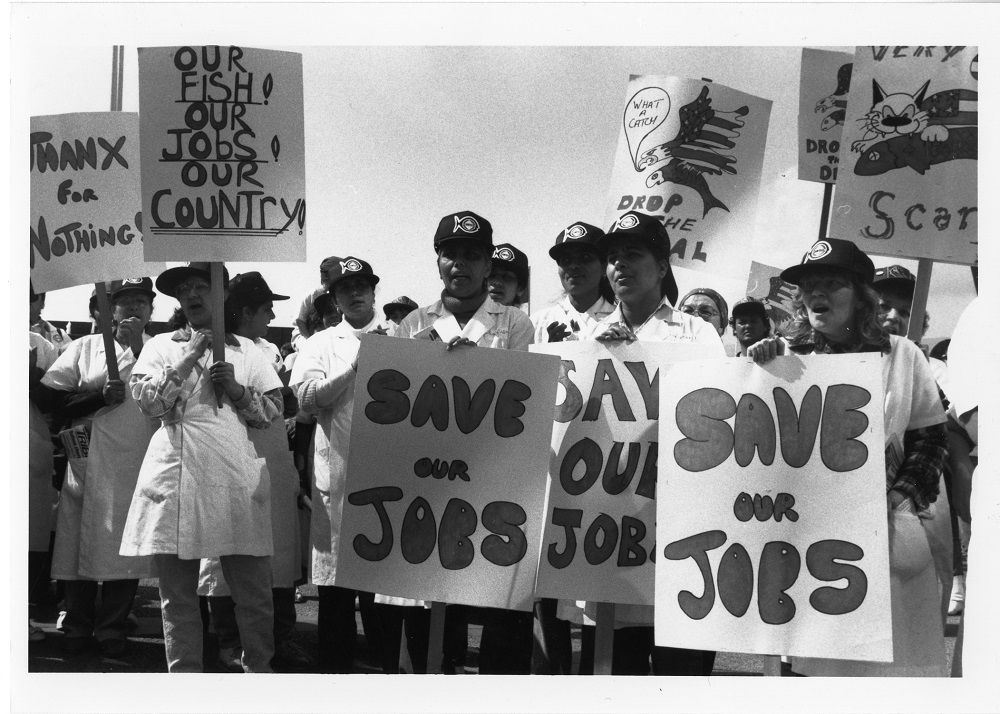 Group of protestors in packing uniforms hold several protest signs