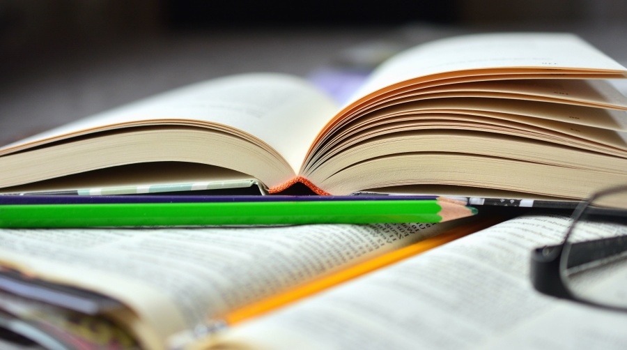 open books with pencils and glasses