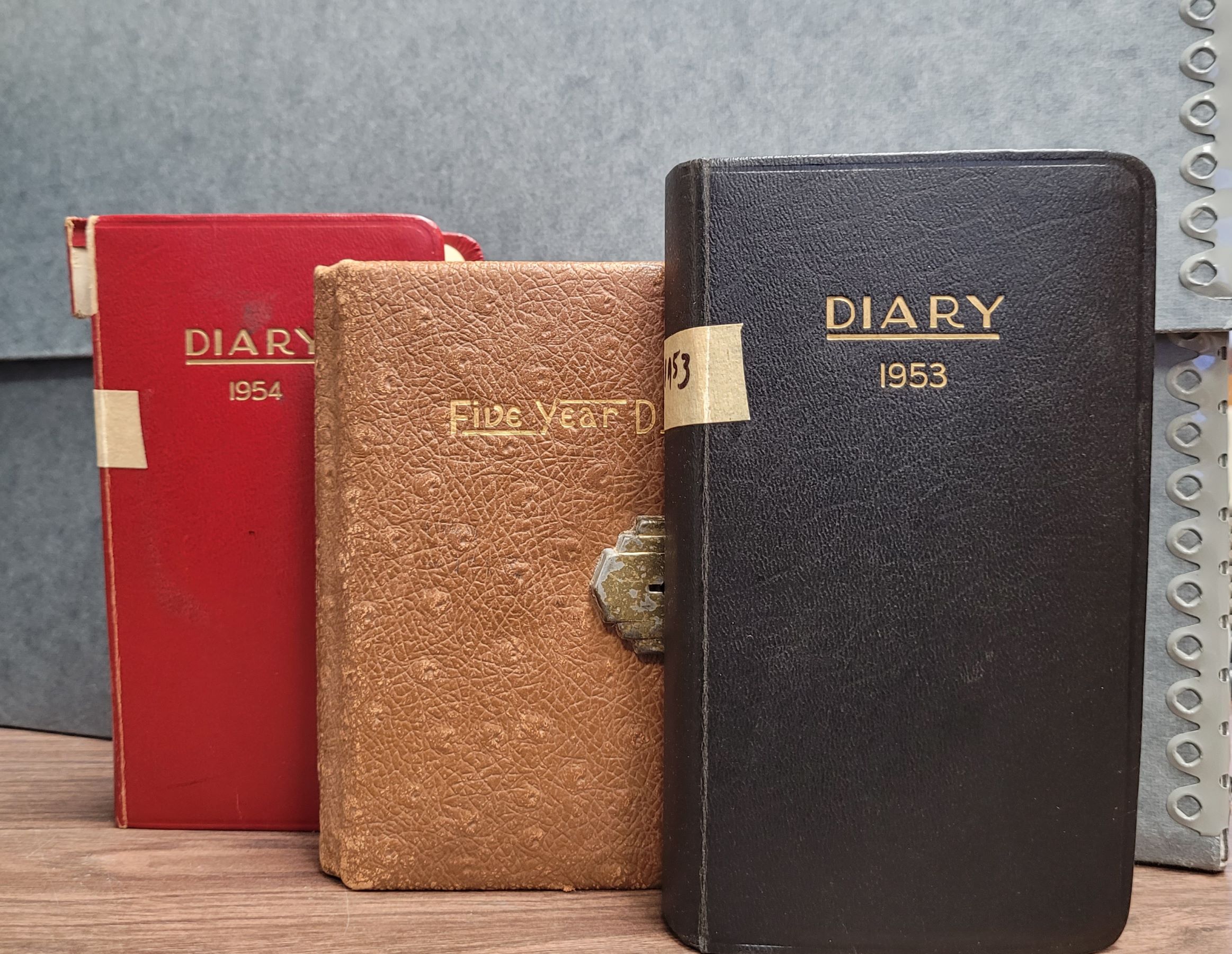 three diaries with a gray archives box