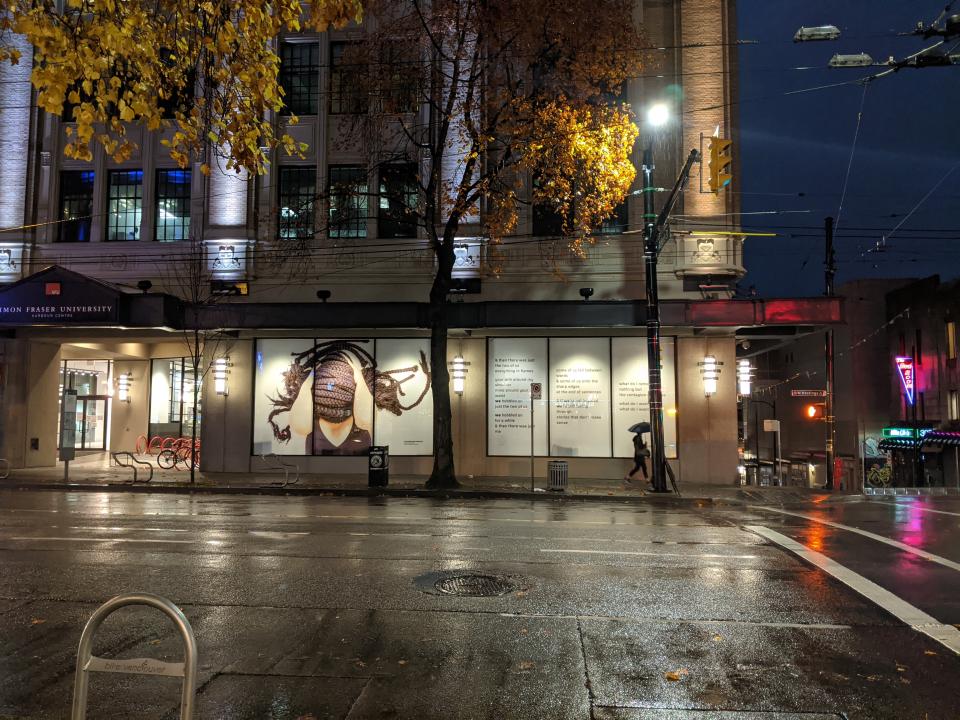 Night view of un/settled in windows of Belzberg Library from across Hastings Street