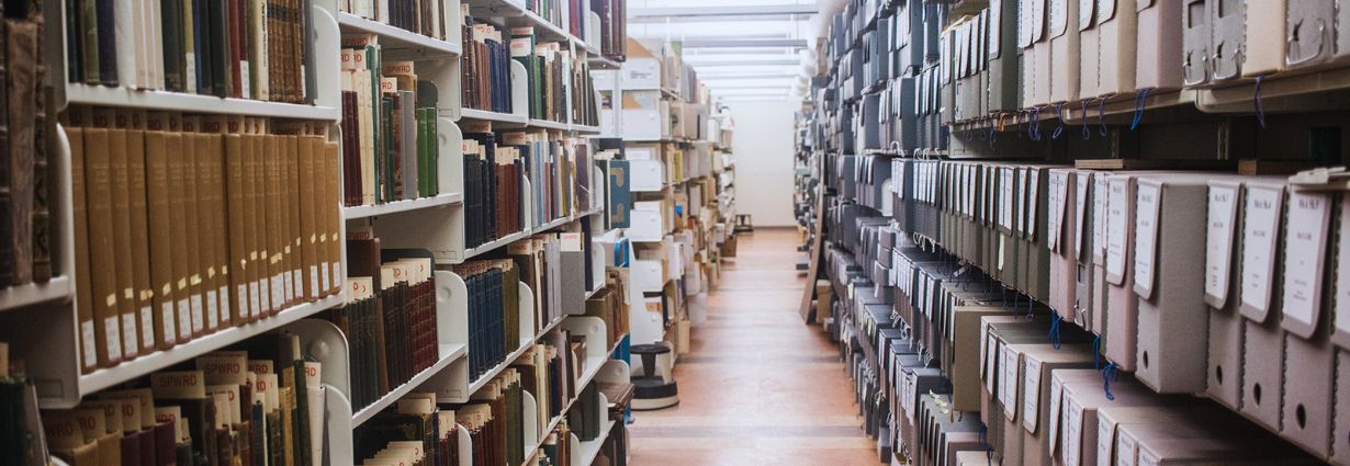 Image inside of the Special Collections and Rare Books vault, featuring a bay of books on the left and grey archival boxes on the right