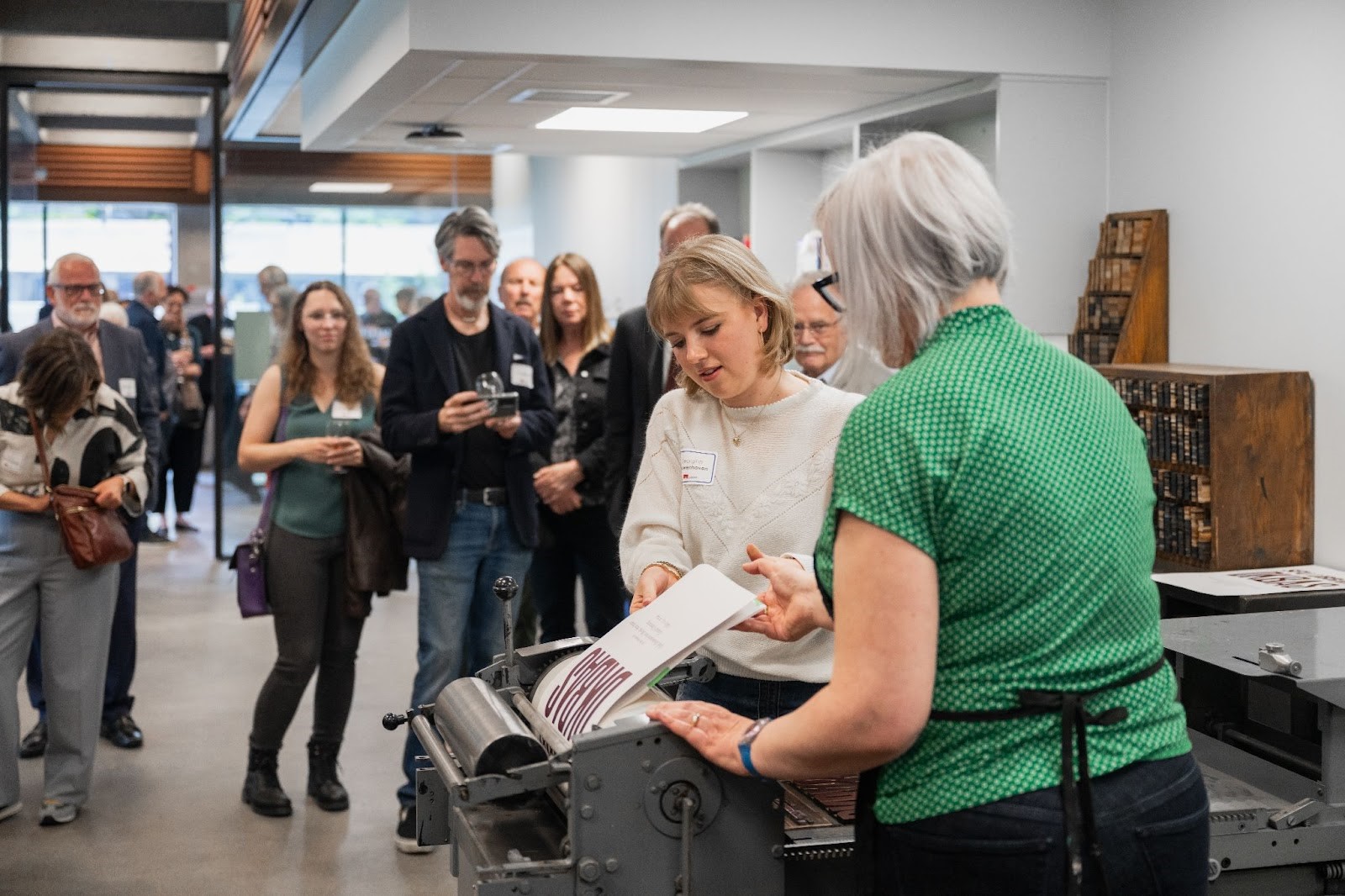 Artist Andrea Taylor shows a letterpress press to a woman.